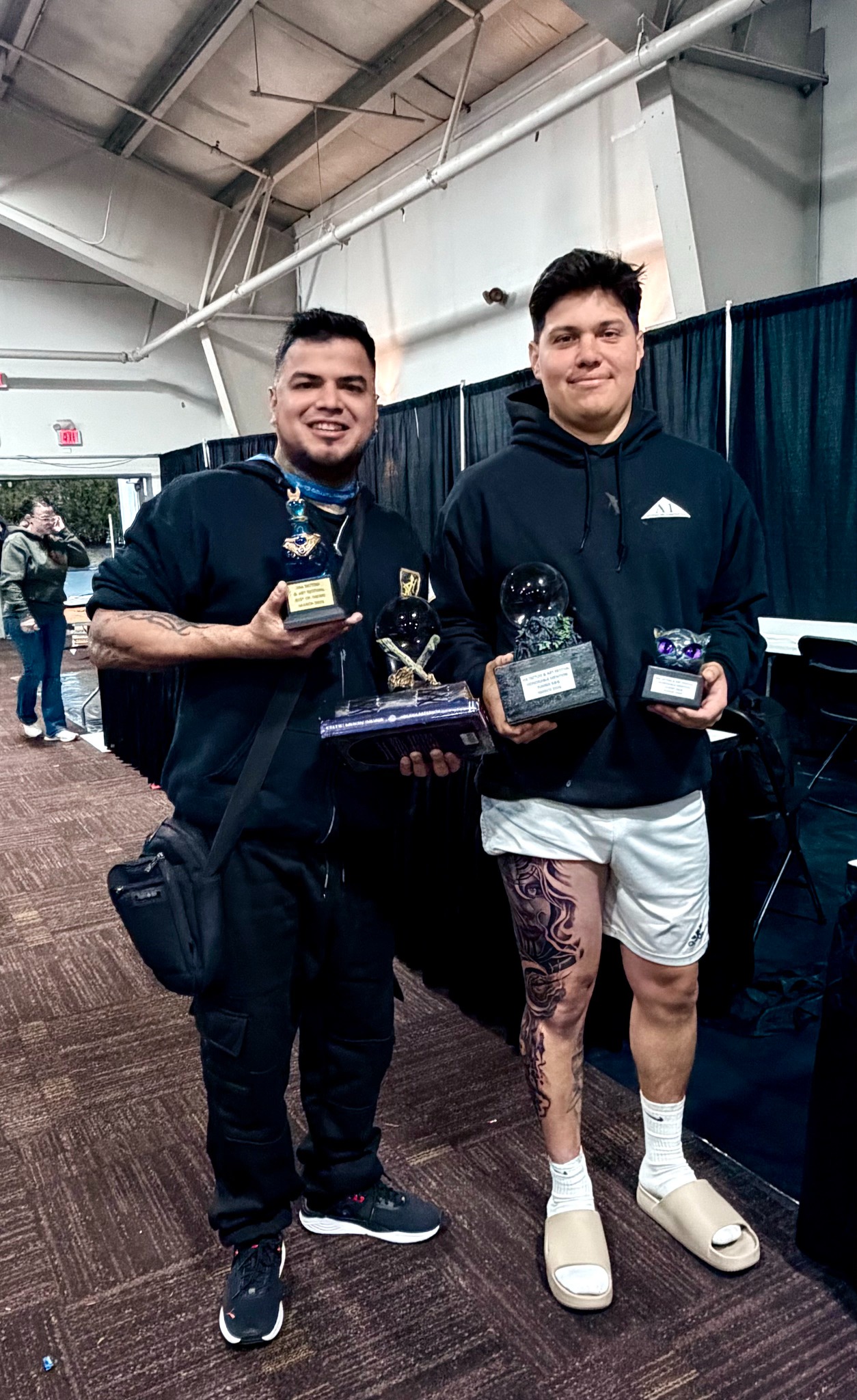 Suicida Ink artist and client holding tattoo convention trophies
