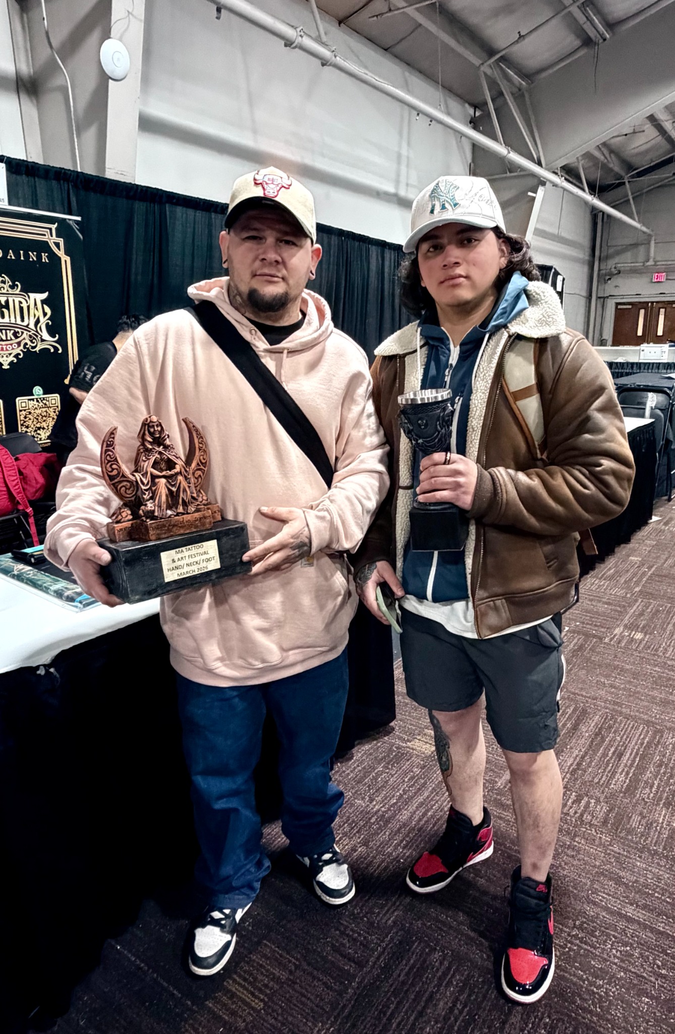 Tattoo convention award recipients holding hand neck and foot trophies